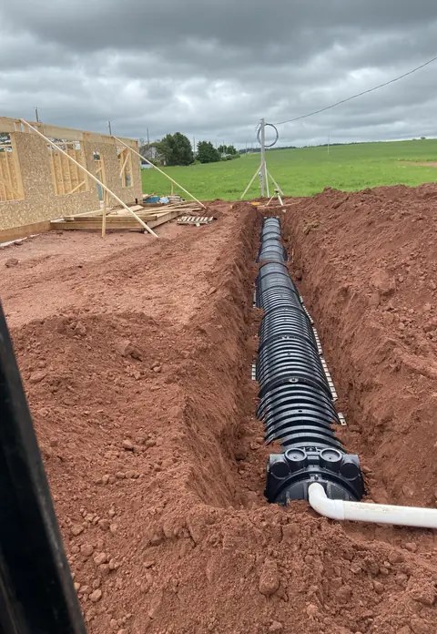 Black chamber run installed in a trench beside a new house frame