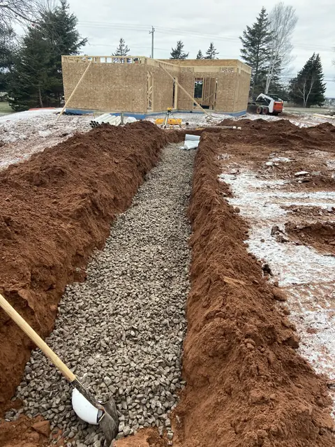 Gravel trench beside a new house frame