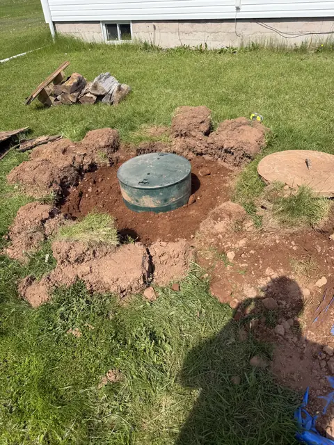 Green septic tank riser exposed in a lawn