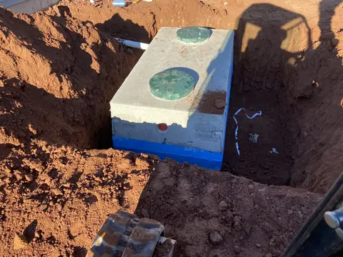Concrete two-lid septic tank with a blue base set in an excavation